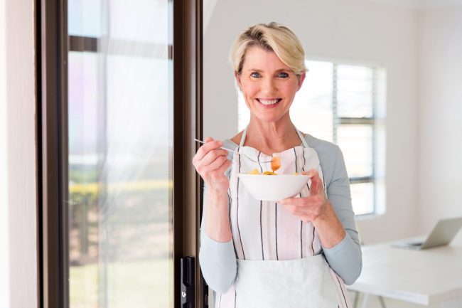 mid age woman eating fruit salad